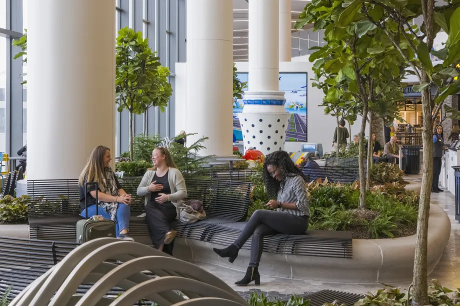 2.	Des personnes assises au milieu d&rsquo;un jardin sensoriel int&eacute;rieur &agrave; l&rsquo;a&eacute;rogare B de l&rsquo;a&eacute;roport LaGuardia, o&ugrave; se trouvent beaucoup de plantes et d&rsquo;arbres, un &eacute;clairage naturel ainsi que des si&egrave;ges dispos&eacute;s en arc.