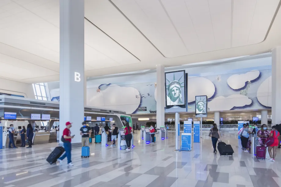 Vue d&rsquo;ensemble de la zone d&rsquo;enregistrement de l&rsquo;a&eacute;rogare B de l&rsquo;a&eacute;roport LaGuardia, qui pr&eacute;sente un am&eacute;nagement ouvert et &eacute;clair&eacute;, des couloirs d&eacute;gag&eacute;s, des bornes libre-service ainsi que des passag&egrave;res et des passagers qui y circulent librement.