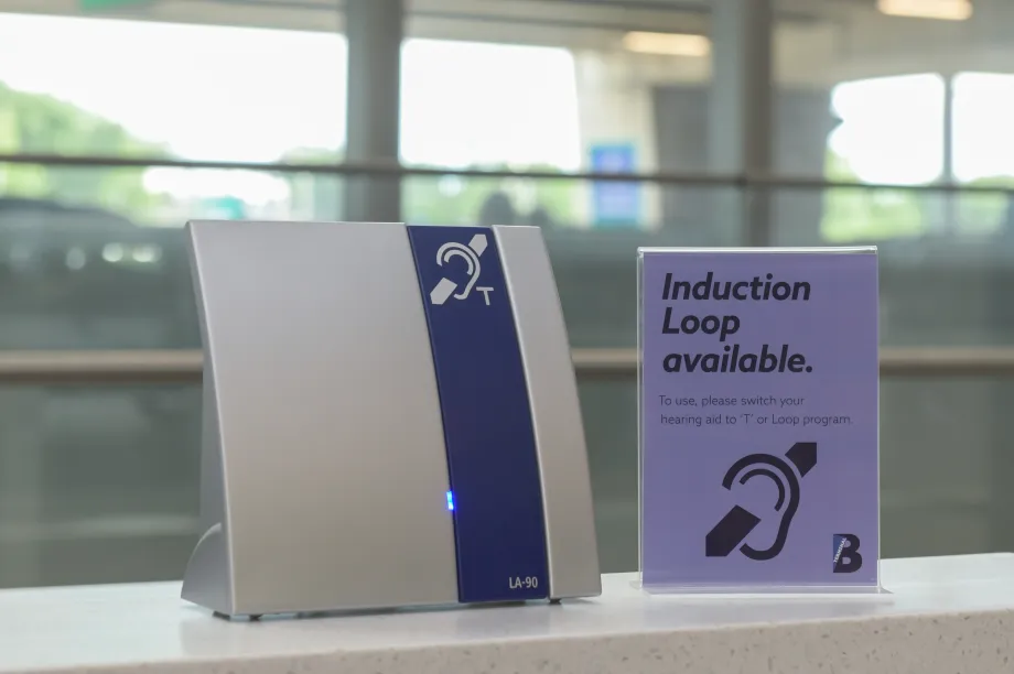 4.	Gros plan sur une affiche pr&egrave;s du comptoir du service &agrave; la client&egrave;le de l&rsquo;a&eacute;rogare B de l&rsquo;a&eacute;roport LaGuardia qui indique qu&rsquo;une boucle &agrave; induction est disponible pour les personnes qui utilisent des proth&egrave;ses auditives.