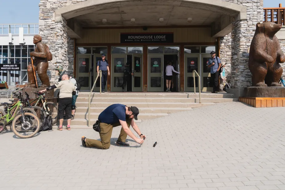 Un homme agenouill&eacute; prend une photo devant un grand portail d'entr&eacute;e avec une rampe incurv&eacute;e.